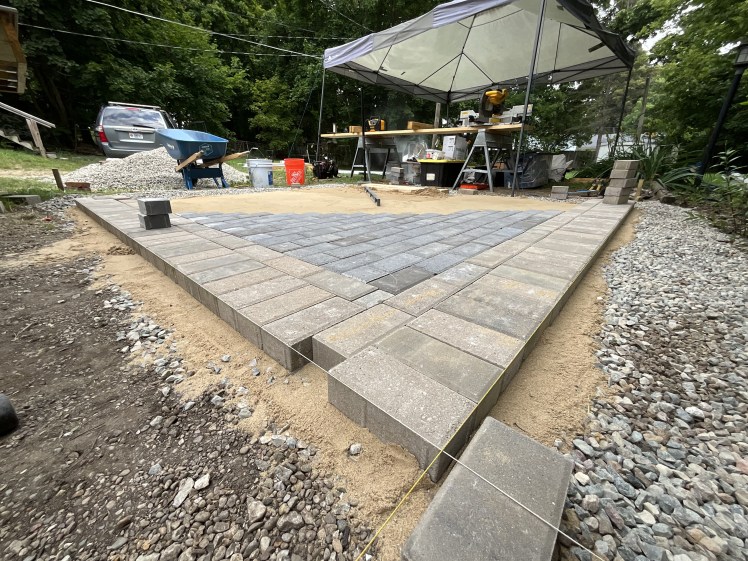 Paver stones being set in place by a construction crew using a line to keep everything straight.