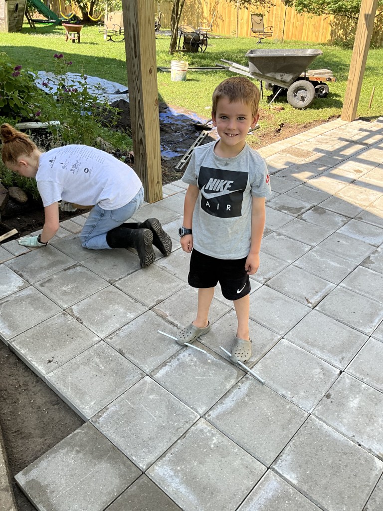 Boy playing with giant nails by putting them through the holes in his crocs. 