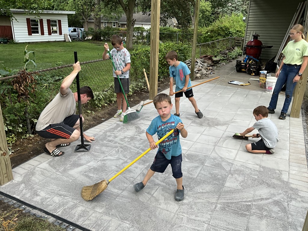 The homeowners boys helping sweep the locking sand for the patio.